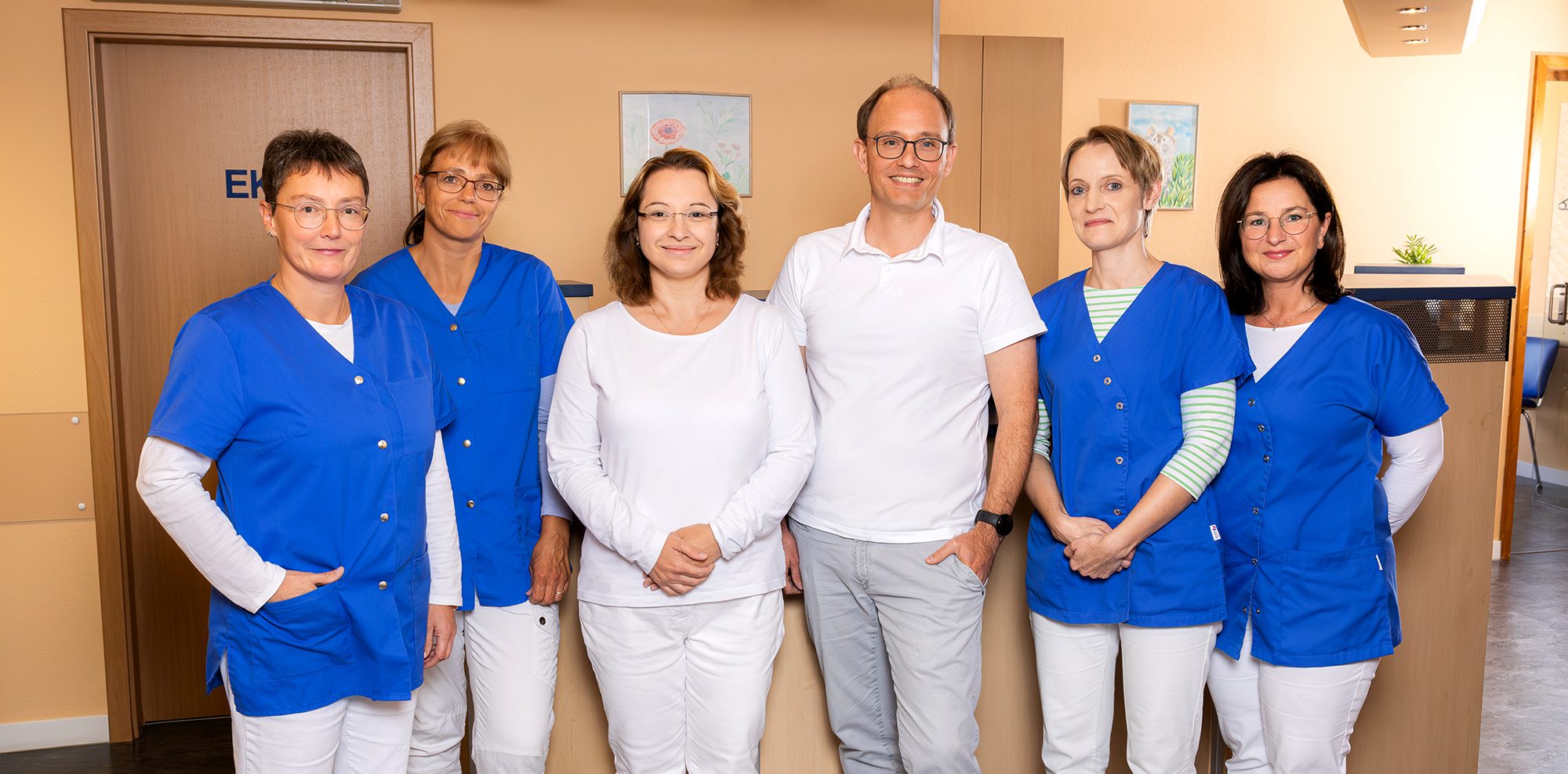 Unser Team Team der Praxis mit Ärzten, lächelnd in einem Flur der Praxis .